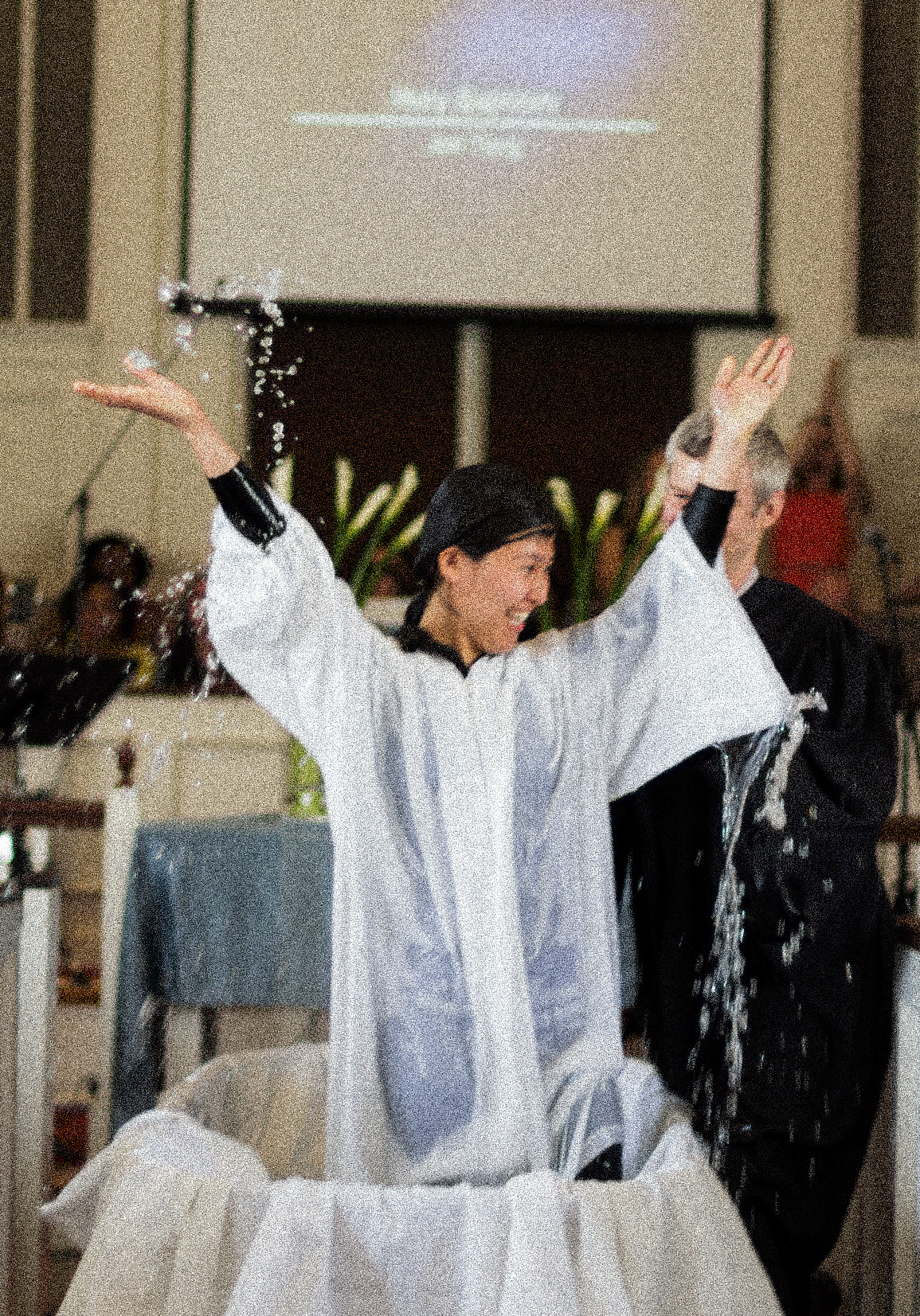 A women throwing her hands up in joy after getting baptized