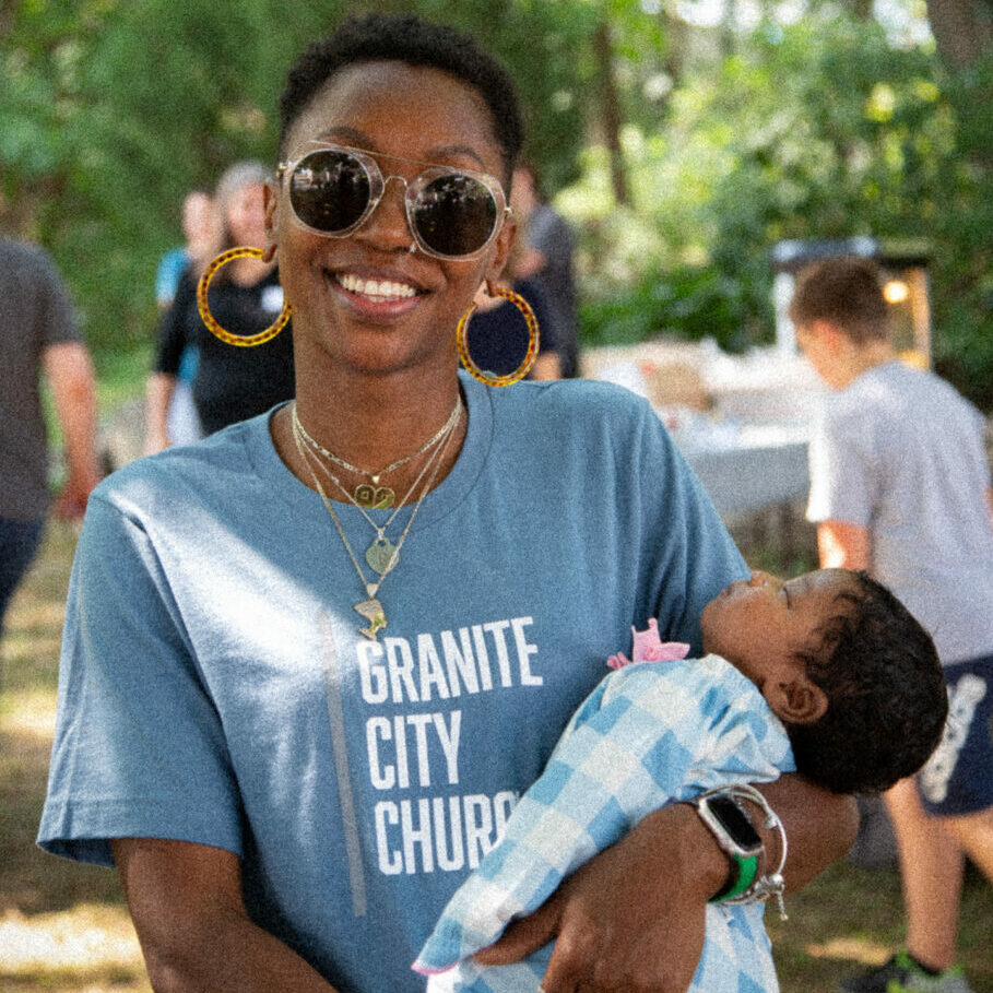 Photo of woman in a Granite City Church t-shirt holding a baby